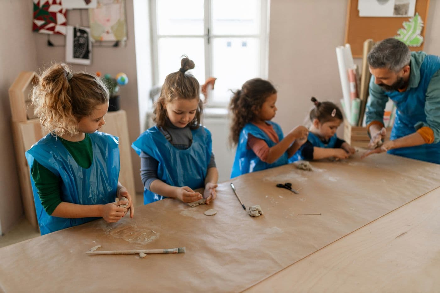 A ceramics teacher working with children at a clay table