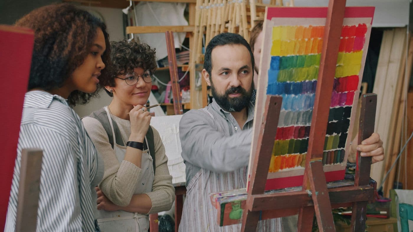 A painting teacher explaining colour to two adult students