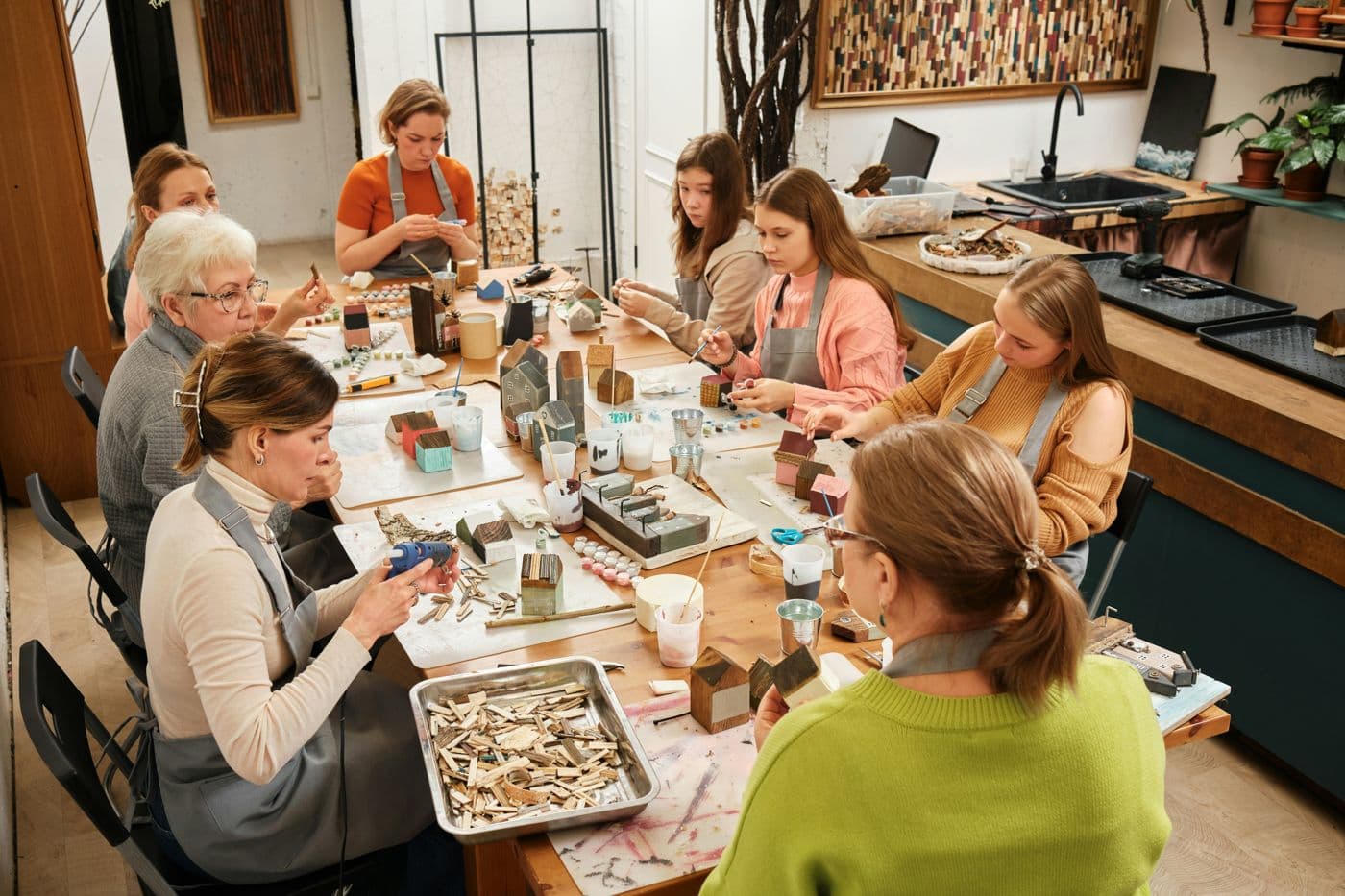 Learners of every age making wooden houses around a workshop table