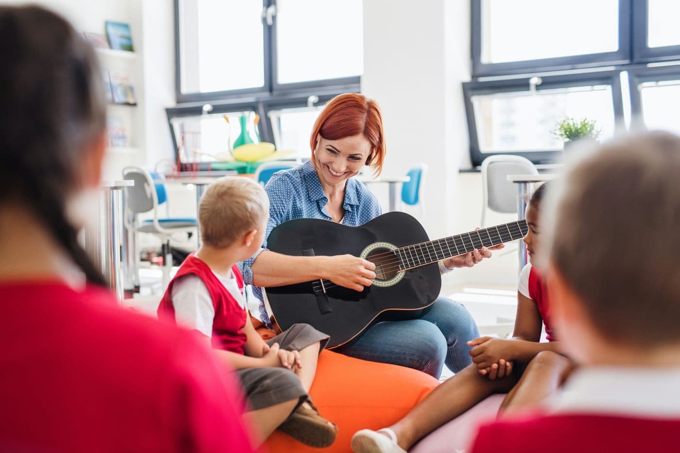 A music teacher playing guitar for a group of children