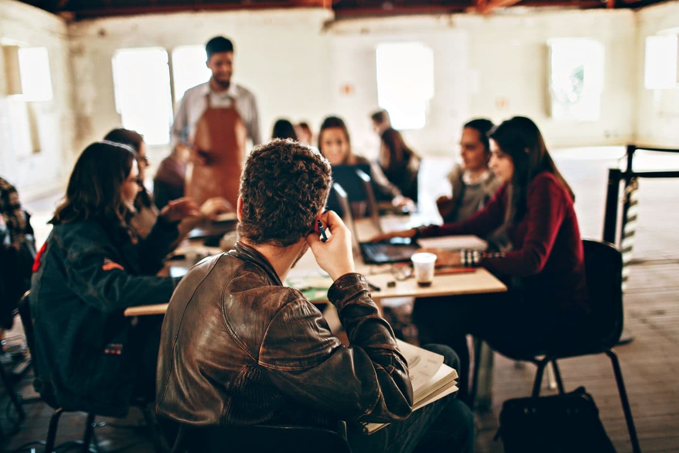 A workshop leader in an apron teaching a group of adults
